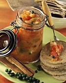 Tomato chutney with green pepper in jar; crisps