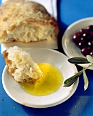 Olive oil with white bread dipped in, on plate; olives