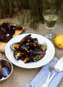 Mussels in vegetable stock on plate on beach; white wine