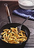 Potato noodles in frying pan on old range
