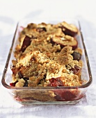 Plum crumble with pine nuts in baking dish