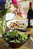 Green salad and pasta salad on laid table in open air