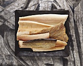 Various types of smoked fish fillets on black platter