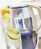 Glass of water with lime and jug with water filter