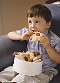 Small boy biting into chocolate hazelnut biscuit