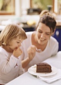 Mother and small daughter eating piece of Sacher torte
