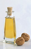 Walnut oil in bottle and two walnuts