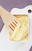 Clarified butter in plastic tub and on a spatula