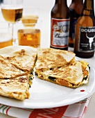 Sweet potato quesadilla on plate in front of beer bottles