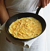 Chef serving omelette in frying pan