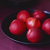 Several nectarines in a black dish