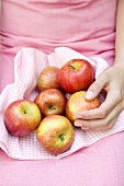Sitzende Frau hält frische Äpfel auf kariertem Tuch