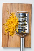 Grated orange peel with grater on chopping board