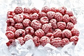 Frozen raspberries surrounded by ice cubes