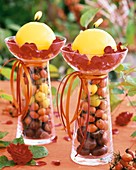 Yellow candles on glasses filled with rose hips & chestnuts