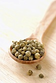 Green peppercorns on wooden spoon