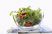Mixed salad leaves with tomatoes and carrots in glass bowl