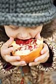 Child biting into pomegranate