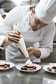 Chef piping cream onto berry desserts