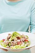 Woman holding plate of avocado, tomato and tuna salad