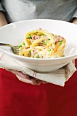 Hands holding plate of macaroni bake