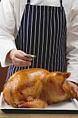 Chef checking roast turkey with meat thermometer
