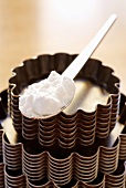 A spoonful of icing sugar on stacked baking tins