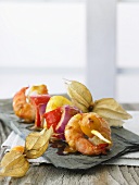 Skewered prawns with fruit, onions and peppers