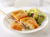 Filled salmon parcels with lemon wedges and salad leaves