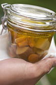 Hand holding jar of pickled mushrooms