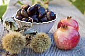 Sweet chestnuts and pomegranates on wooden table