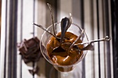 Chocolate mousse in a glass with several spoons (overhead)
