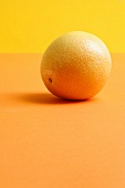 Eine Grapefruit auf orangefarbenem Hintergrund