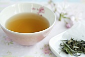 Tea in pink bowl, tea leaves and cherry blossom