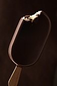 Chocolate-coated vanilla ice cream on a stick, a bite taken