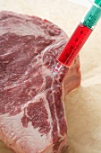 Raw beef steak with syringe (food additives)