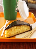 Piece of cream cake with chocolate glaze, coffee cup (USA)