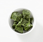Cubes of frozen spinach in white bowl (overhead view)