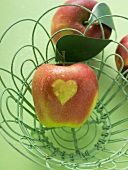 Red apples with heart in and beside wire basket
