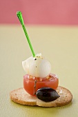 Tomato and mozzarella on cocktail stick and olive on toast