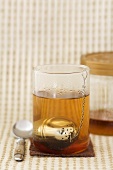 A glass of black tea with honey and tea infuser