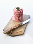 A ball of kitchen string on chopping board with knife