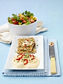 Hummus mit Knäckebrot, bunter Salat im Hintergrund
