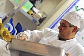 Chef emptying roasting tin in commercial kitchen
