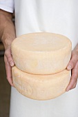 Man holding two round cheeses (Bauernkäse, farmhouse cheese)