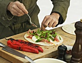 Topping a piadina with rocket and raw ham