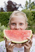 Girl holding a slice of watermelon out of doors