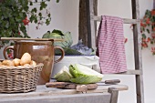 Rustikales Stillleben mit Kartoffeln und Kohl vor Bauernhaus