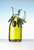 Olive oil in glass jug with olive sprig