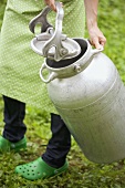 Woman carrying a large milk can